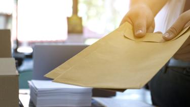 Office clerk or secretary handing over documents and brown envelopes