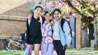 3 elementary students 3 female elementary students in Abbotsford, BC underneath blossoming cherry trees