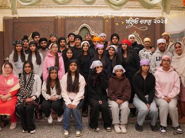 A group of students and a teacher grouped together for a photo on a field trip to the Gobind Sarvar.