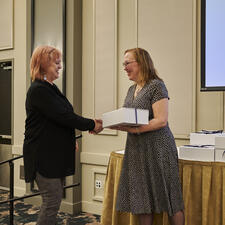 Trustee Wilson gifting a long service service gift box to a female employee