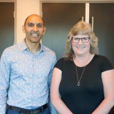 Male principal stands with female retiree and poses for photo