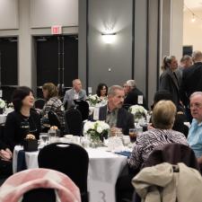 Attendees sitting at tables or standing and mingling