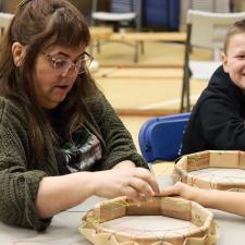 Students watching a demonstration of making a drum.