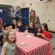 A small group of students and staff sitting at a table, enjoying a sweet treat