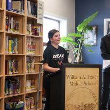 Female student stands at podium speaking about the project