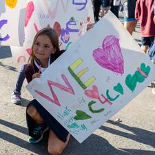 Young female student holds sign up for Cops for Cancer.